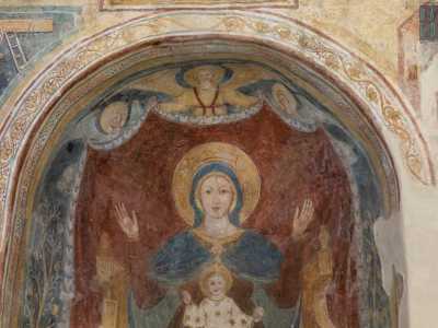 Ha sul grembo Ges� benedicente con il globo sulla mano sinistra. In alto tre angeli reggono il drappo color rubino che fa da sfondo all�opera